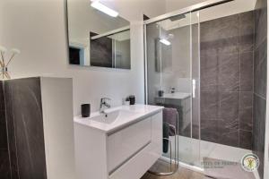 a bathroom with a white sink and a shower at La maison du pont in Trédarzec