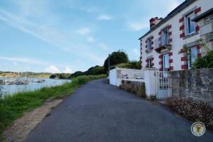 a road next to a building next to a river at La maison du pont in Trédarzec