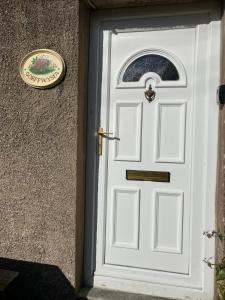 eine weiße Tür mit einem Schild an der Seite eines Gebäudes in der Unterkunft Cosy cottage in Snowdonia hamlet in Frongoch