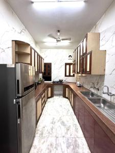 a large kitchen with wooden cabinets and a black refrigerator at Fortune Home Service Apartment 2Bhk ,E28 Saket 1A in New Delhi