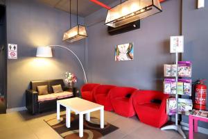 a living room with red chairs and a table at Hotel O Link Inn in Johor Bahru