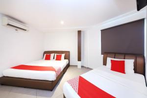 two beds in a room with red and white at Hotel O Link Inn in Johor Bahru