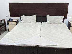 two beds with white sheets and pillows in a bedroom at Kadambari hotel in Maihar