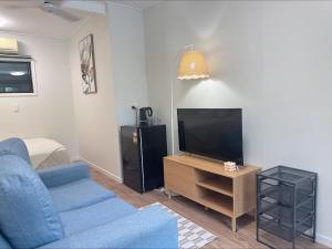 a living room with a blue couch and a flat screen tv at Haven39 in Bayview Heights