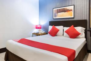 a bedroom with a large bed with red pillows at Orange Nest Hotel in Manila