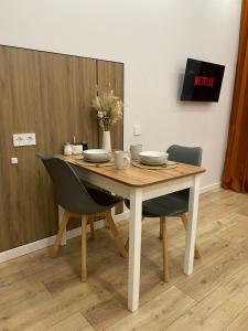 a dining room table with two chairs and a table with plates at Contento Apartments in Almaty