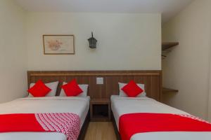two beds in a room with red pillows at Hotel O The Vintage Hotel in Nusajaya