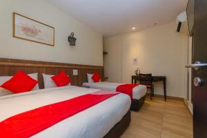 a hotel room with two beds and a desk at Hotel O The Vintage Hotel in Nusajaya