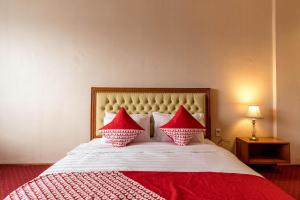 a bedroom with a bed with two red pillows at Capital O 293 Mutiara Hijau Suites Syariah in Medan