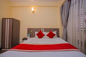 una camera da letto con un letto grande con cuscini rossi di OYO 297 Hotel Aayam a Kathmandu