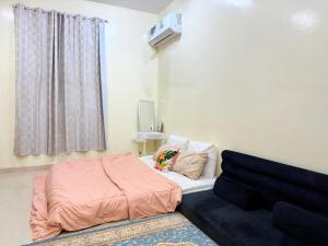 una piccola camera da letto con un letto e un divano di BlessyWail Homestay a Mascate