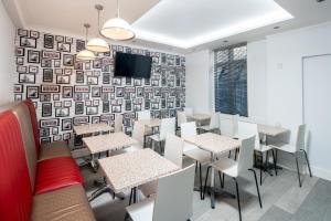 a restaurant with tables and chairs and a tv on a wall at OYO Bakers Hotel London Victoria in London