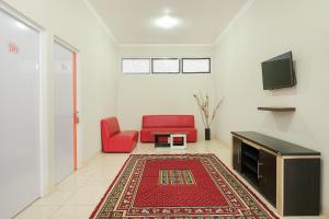 a living room with a red couch and a tv at Hotel O Banguntapan Near Galaxy Waterpark Formerly Hotel Desa Puri in Yogyakarta