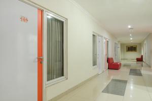 a hallway of a hospital with a red chair and windows at Hotel O Banguntapan Near Galaxy Waterpark Formerly Hotel Desa Puri in Yogyakarta