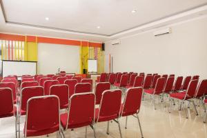 a conference room with red chairs and a podium at Hotel O Banguntapan Near Galaxy Waterpark Formerly Hotel Desa Puri in Yogyakarta