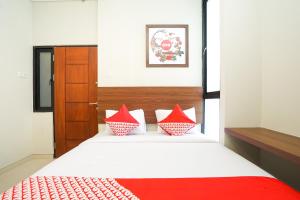 una camera da letto con un letto con cuscini rossi e bianchi di Super OYO Capital O 449 The Colins a Keputih