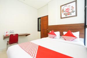 una camera da letto con un letto con cuscini rossi e bianchi di Super OYO Capital O 449 The Colins a Keputih