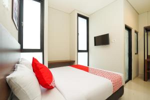 una camera da letto con un letto con cuscini rossi e bianchi di Super OYO Capital O 449 The Colins a Keputih