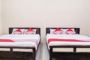 two beds in a room with red and white pillows at Hotel O Central Batu Near Jatim Park 3 Formerly Bunga Matahari Hotel in Batu