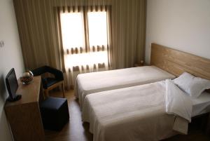 a hotel room with a bed and a chair and a window at Santa Noite in Fátima