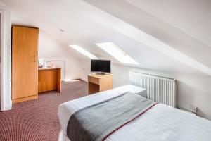 a attic bedroom with a bed and a television at London Guest House by OYO - Acton in London
