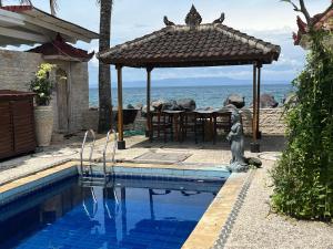 a swimming pool with a gazebo next to the ocean at Catra Homestay beachroom 10 B in Karangasem