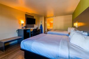 a hotel room with two beds and a flat screen tv at OYO Hotel Yoakum West in Yoakum
