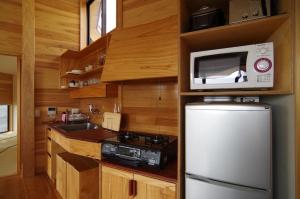 a kitchen with a refrigerator and a microwave at Cottage Views in Yakushima