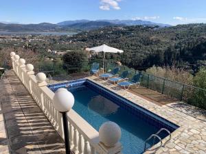 a swimming pool on a balcony with chairs and an umbrella at Villa Mike's House in Apolpaina