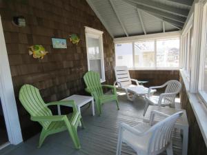 a porch with green chairs and a table and chairs at Bay Views! Wifi Bay Side Duplex In Ship Bottom in Ship Bottom +1 photo