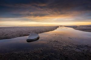 a rock sitting in the middle of a beach at River Camp in Lembuži