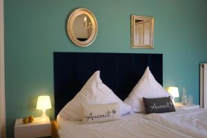 a bedroom with a bed with white pillows and a mirror at Apartment Kaiserperle mit Balkon direkt am Strand in Lübeck