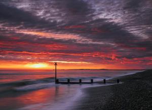 a sunset over the ocean with a pier on the beach at Findhorn Bay - Mobile Holiday Homes in Findhorn