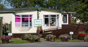 a small house with flowers in front of it at Findhorn Bay - Mobile Holiday Homes in Findhorn