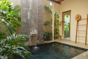 a pool with a waterfall in a house with plants at Mamori House at Kohlarn in Ko Larn
