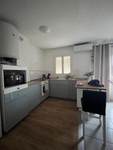 a kitchen with grey cabinets and a table and a chair at Appartement climatisé avec parking à Albi in Albi