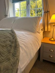 a bedroom with a bed with white sheets and a window at Holly Bank Cottage in Brenchley