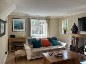 a living room with a couch with colorful pillows at Holly Bank Cottage in Brenchley