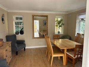 a dining room with a table and chairs and a mirror at Holly Bank Cottage in Brenchley