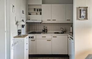 a white kitchen with a sink and a refrigerator at 1 Bedroom Amazing Apartment In Løkken in Løkken