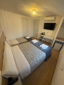 Habitación pequeña con 2 camas y TV. en Hostal Esparteros, en Madrid