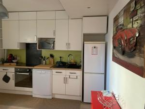 a kitchen with white cabinets and a refrigerator at Appartement cosy - Paris La Défense in Courbevoie