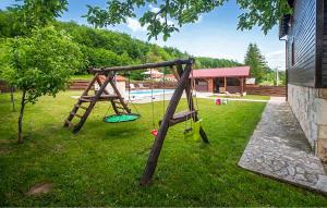 a swing set in the grass next to a pool at Stunning Home In Gospic in Gospić