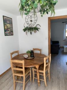 a dining room table with four chairs and a clock at Appartement 2/4 personnes in Bussang