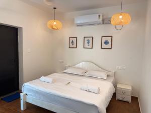 a bedroom with a bed with white sheets and a fan at Dariya Sea Front by Beach County in Udupi +46 photos
