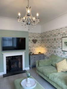 a living room with a green couch and a fireplace at Beautiful 3 bedroom house close to Lowestofts south beach in Lowestoft