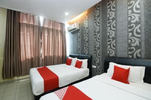 two beds in a hotel room with red pillows at Hotel O Ys Inn in Miri