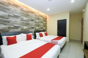 two beds in a hotel room with red pillows at Hotel O Ys Inn in Miri