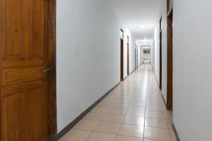 a hallway with white walls and a wooden door at Hotel O Pantai Jaya in Pangandaran