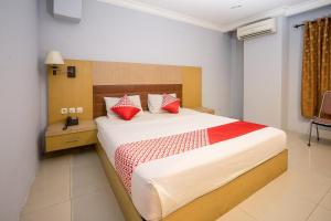 a bedroom with a large bed with red pillows at Hotel O Mega Sentosa in Samarinda